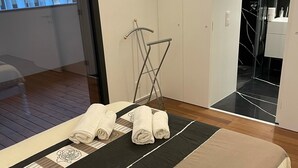 Een moderne slaapkamer met een groot bed, een houten vloer en uitzicht op een balkon.