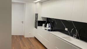 Een moderne keuken met witte kastjes, een zwarte spatwand en houten vloeren.