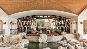 Un espace extérieur aménagé, abrité et doté de sièges, avec une piscine, le tout entouré de rochers et de plantes.