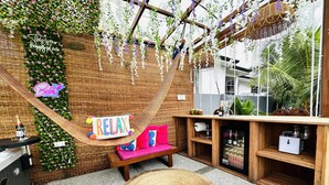 Une pièce accueillante avec un hamac, un panneau indiquant «Détendez-vous», un petit canapé, une armoire en bois et un fauteuil en osier.