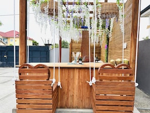 Un coin bar en bois, agrémenté de suspensions florales et d’une bouteille de vin.