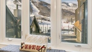Una habitación con ventanas amplias que ofrecen vistas a un paisaje nevado de montaña.