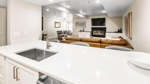Una cocina moderna con una isla grande, un lavaplatos empotrado y una zona de comedor con un sofá y sillas.