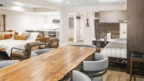 Una sala moderna con una mesa de comedor de madera, sillas tapizadas en gris y un sofá con cojines estampados.