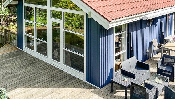 A blue building with large windows, a wooden deck, and outdoor furniture. - 3 bedroom beautiful home in Vig (Vig)