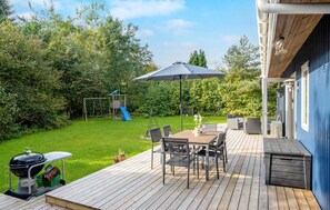 A wooden deck with a table and chairs, a barbecue grill, and a children's play structure. - 3 bedroom beautiful home in Vig (Vig)