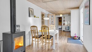 A cozy kitchen with a wood stove, wooden chairs, a dining table, and white cabinets. - 3 bedroom beautiful home in Vig (Vig)