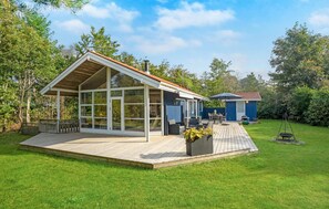 A modern house with a large glass extension, a wooden deck, and a small blue shed in a lush garden. - 3 bedroom beautiful home in Vig (Vig)