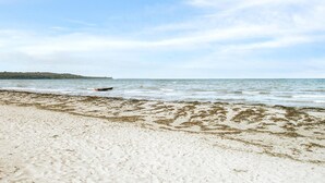 A beach with a boat on the water and a distant landmass. - 3 bedroom beautiful home in Vig (Vig)