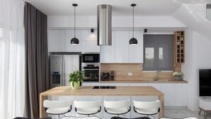A modern kitchen with a central island, stainless steel appliances, and pendant lighting.