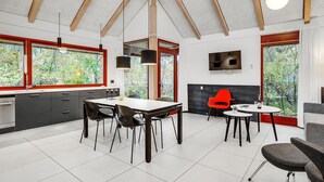 A modern kitchen with a dining area, large windows, and a TV on the wall. - Nice home in Grenaa with kitchen (Grenaa)
