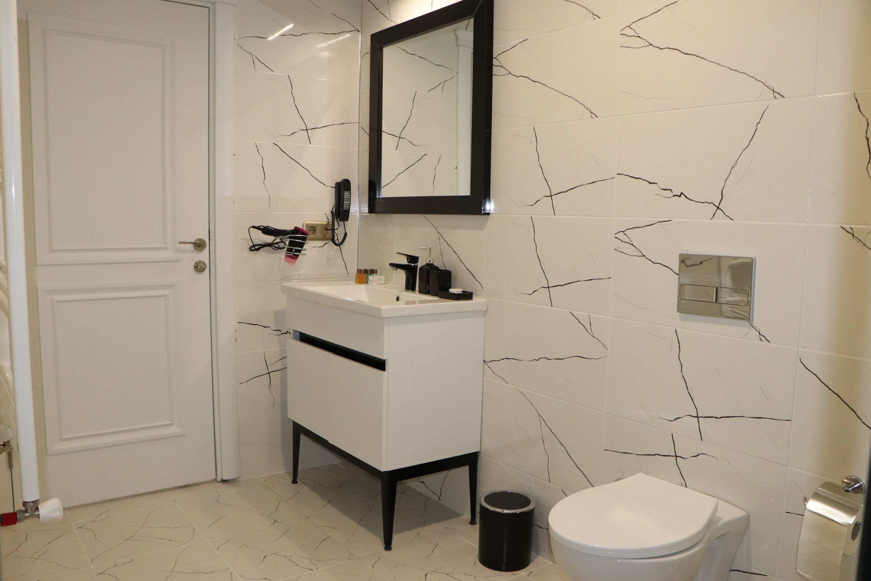 Un baño con tocador blanco, inodoro y espejo.