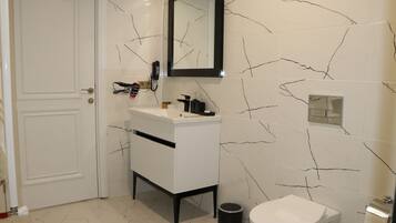 Un baño con tocador blanco, inodoro y espejo.