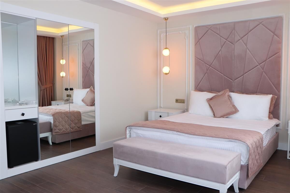 Un dormitorio con cama, mesitas de noche, un espejo y un banco.