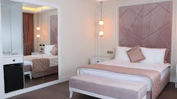 Un dormitorio con cama, mesitas de noche, un espejo y un banco.