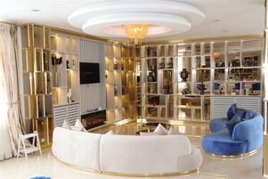 Un salón elegante con un sofá blanco, un sillón azul y una mesa de centro de cristal.