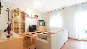 En moderne stue med sofa, fjernsyn, træskab og spiseplads.