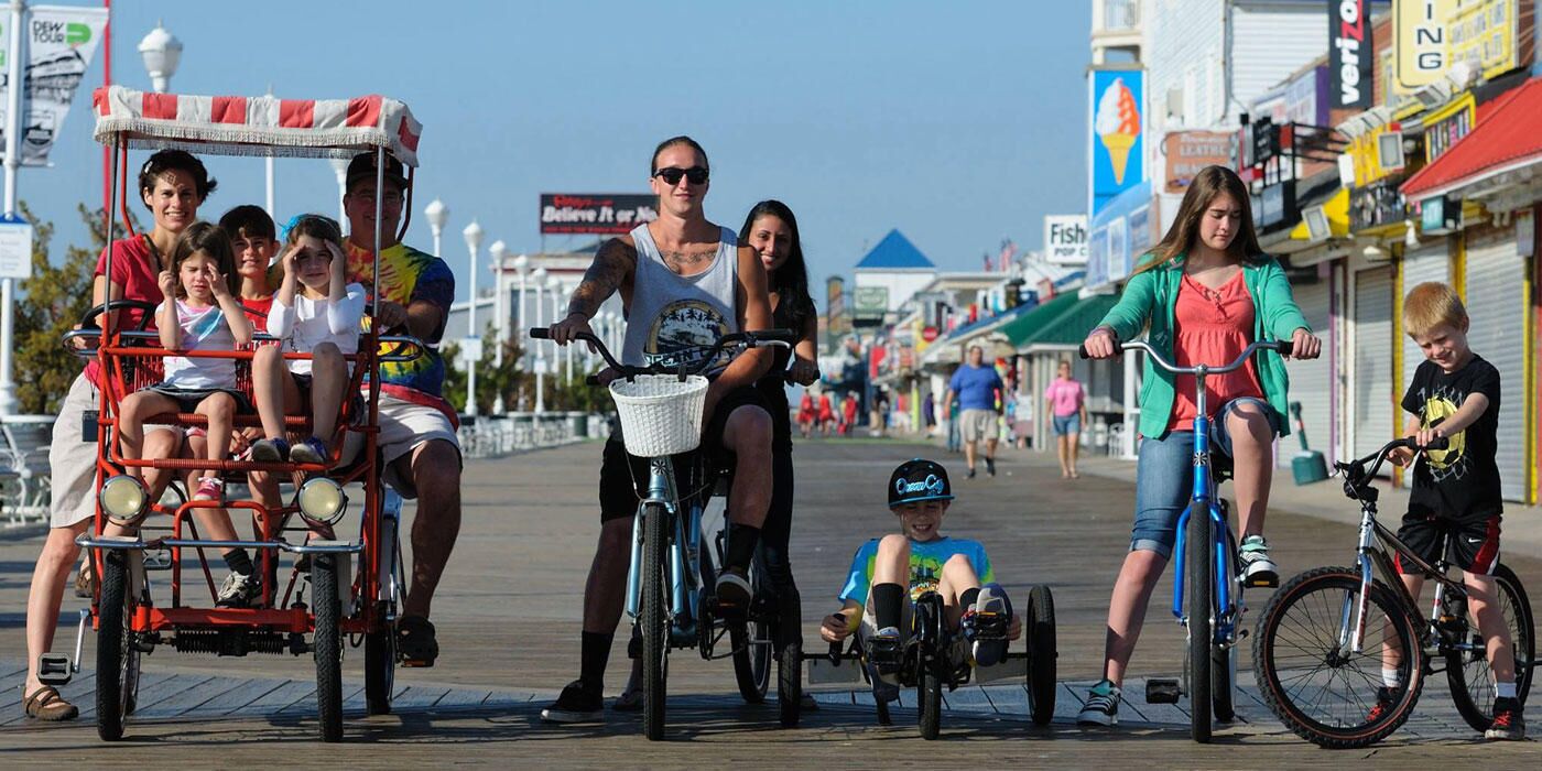 A boardwalk with people riding bicycles and a trolley.