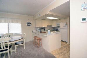 A compact kitchen with a dining area, featuring a refrigerator, microwave, and a small island counter.
