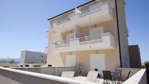 A multi-story building with balconies, outdoor seating, and a view of the sea. - Amazing apartment in Podstrana with WiFi (Podstrana)