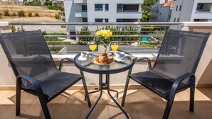 A balcony with two chairs, a small table, and a vase with yellow flowers. - Amazing apartment in Podstrana with WiFi (Podstrana)