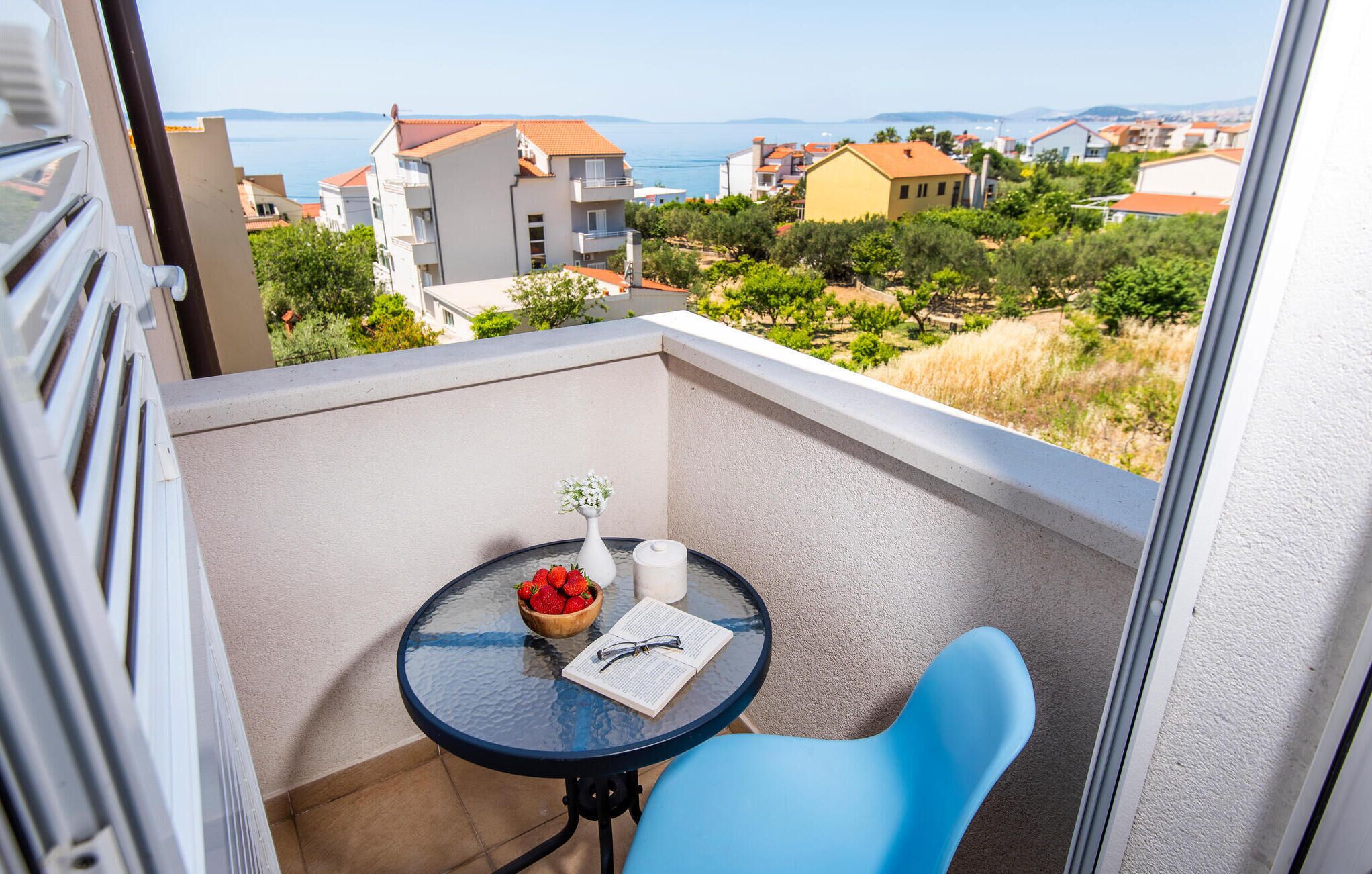 Uma varanda com mesa, cadeira e vista para o mar e edifícios.