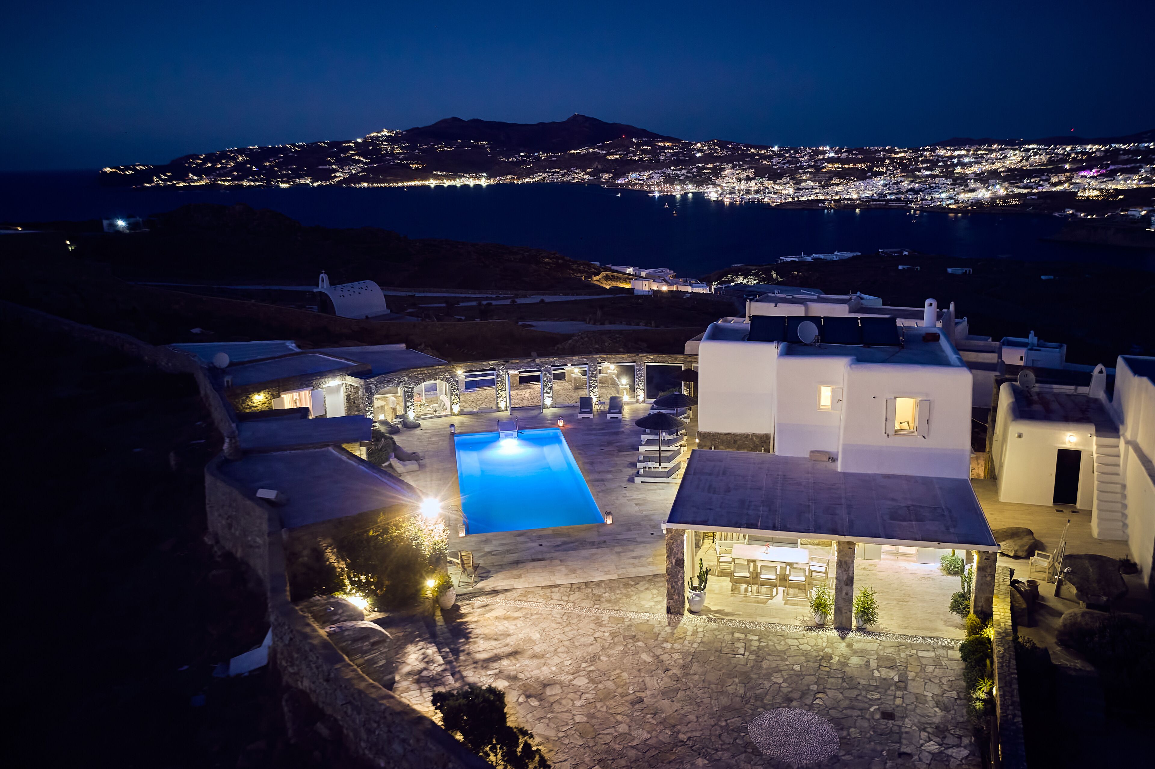 Zona de piscina al terrat amb vista a la ciutat de nit.