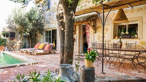 A courtyard with a pool, lounge chairs, a dining table with chairs, and a large tree. - Stunning home in ROUJAN (ROUJAN)