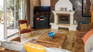 A cozy living room with a fireplace, a television, and a comfortable seating area. - Stunning home in ROUJAN (ROUJAN)