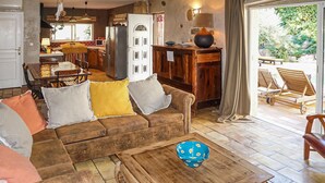 A cozy living room with a brown sofa, a wooden coffee table, and a dining area with a wooden table and chairs. - Stunning home in ROUJAN (ROUJAN)