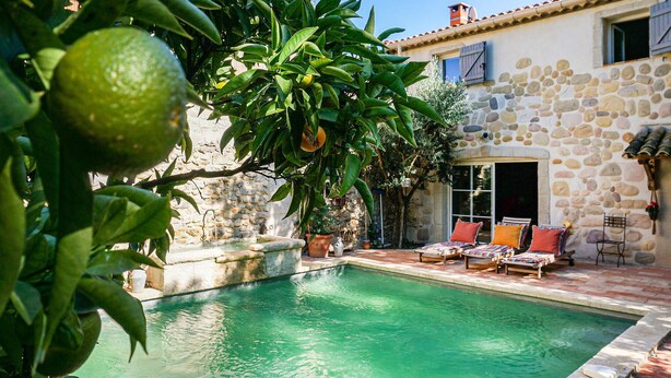 A stone building with a swimming pool, outdoor seating, and a potted plant. - Stunning home in ROUJAN (ROUJAN)