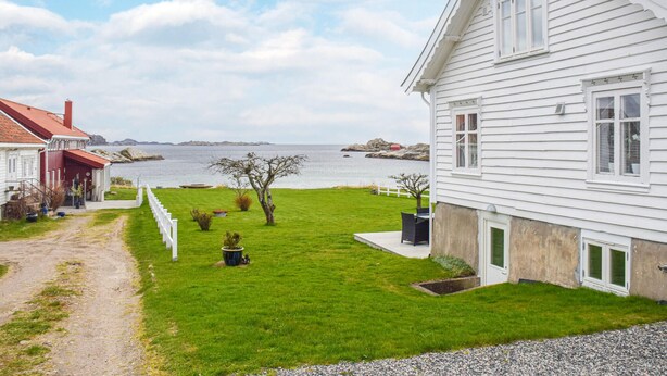 A white house with a red roof, a grassy yard, and a view of the sea. - 3 bedroom cozy home in Lindesnes (Lindesnes)
