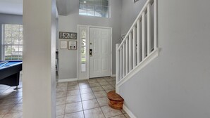 A hallway with a pool table, a white door, and a staircase.