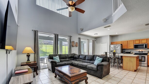 A spacious living room with a sectional sofa, a wooden coffee table, and a ceiling fan.