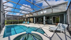 A pool area with a glass ceiling, lounge chairs, and a small hot tub.