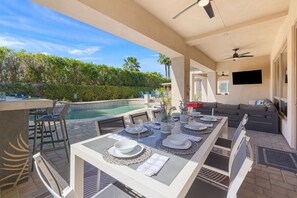 An outdoor dining area with a pool, bar, and seating.