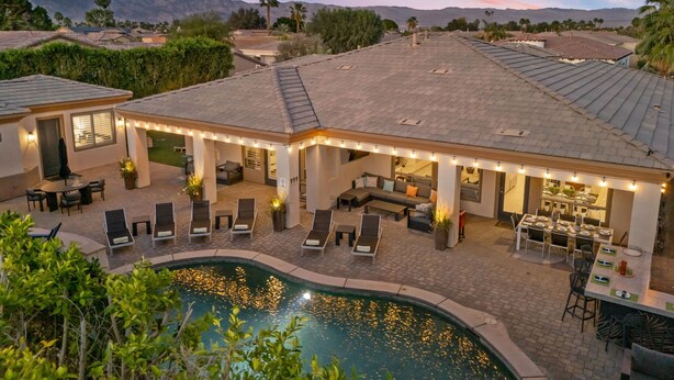 Una propiedad residencial con piscina, mobiliario exterior y un patio cubierto.