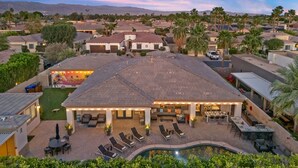 Zona residencial con una casa grande que tiene un patio con mobiliario exterior y una piscina.