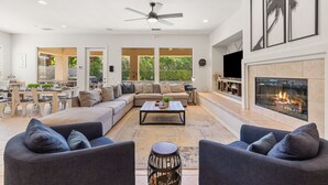 Un amplio espacio de sala con un sofá grande, dos sillones, una mesa de centro y una chimenea.