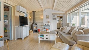 Un salon chaleureux avec une cheminée, un téléviseur et un canapé confortable.