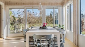 Un coin repas avec une table blanche, des chaises grises et un luminaire suspendu.