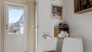 Une salle de bain avec une porte en bois, un porte-rouleau de papier toilette, un porte-serviettes et une petite étagère contenant des articles de toilette.