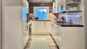 Eine moderne Küche mit weißen Schränken, einer Holz Arbeitsplatte und Blick auf Bäume durch ein Fenster.