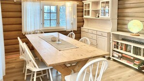 Ein Holzblockhaus-Interieur mit einem Esstisch, Stühlen, einem Bücherregal und einem Globus.