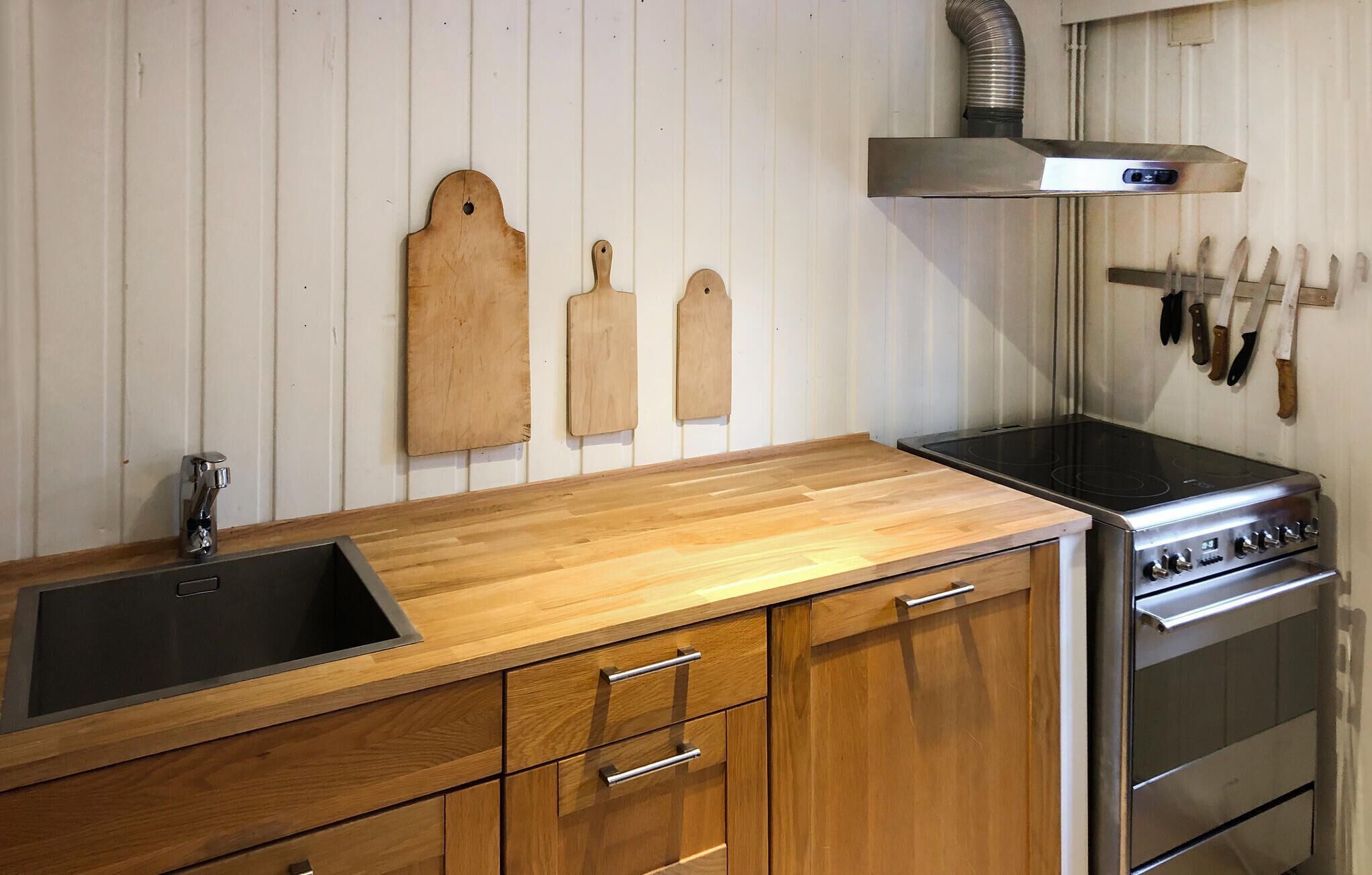 A kitchen with a wooden countertop, stainless steel stove, and a sink.