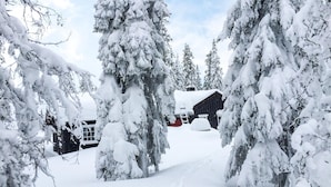 A snow-covered landscape with a wooden cabin and a red vehicle parked in front. - Nice home in Sjusjøen with WiFi (Sjusjøen)