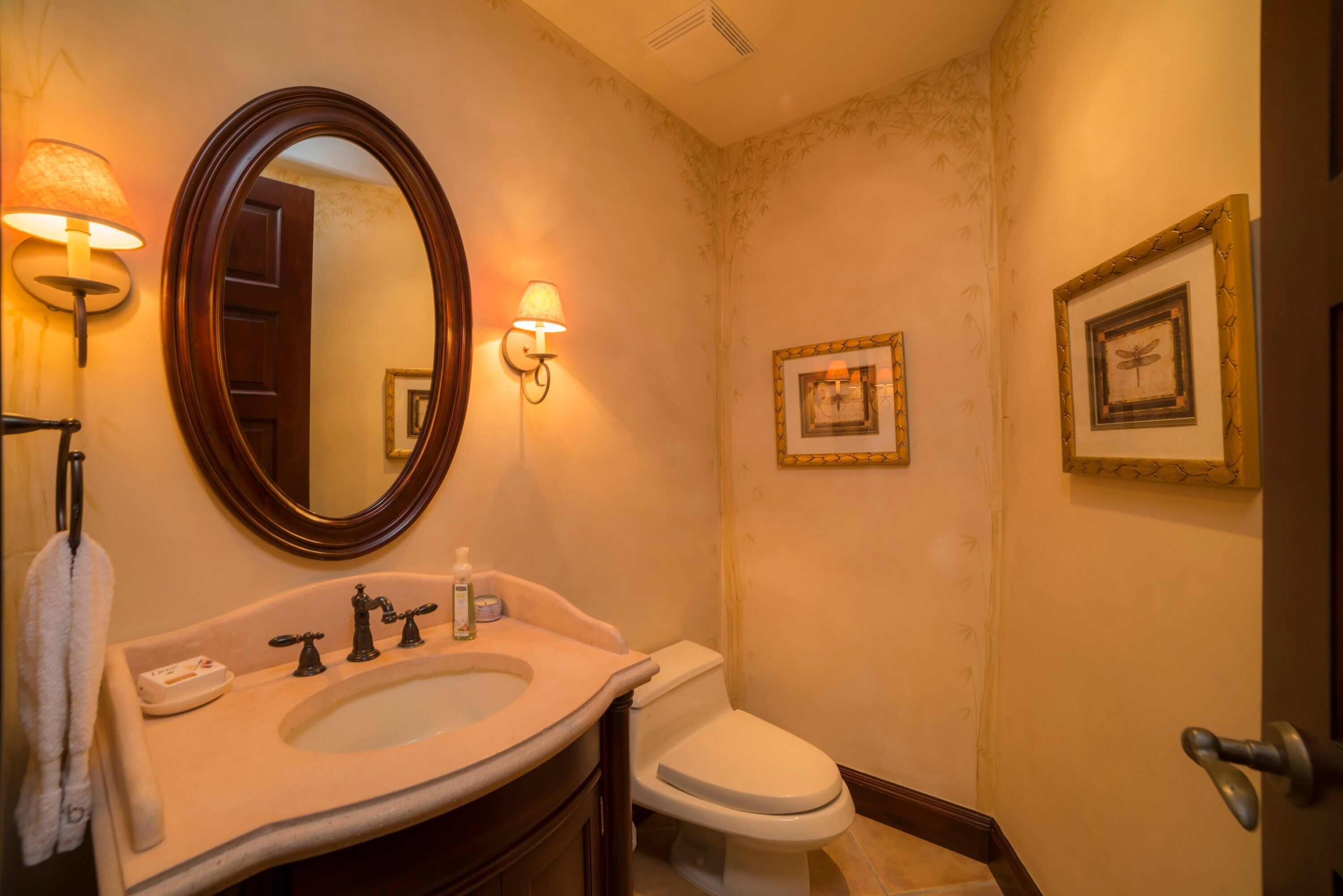 Een badkamer met een wastafel, spiegel, toilet en wanddecoraties.