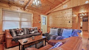 A cozy log cabin interior with two sofas, a coffee table, and a door leading to another room. - Log Cabin in the Woods (Arkdale)