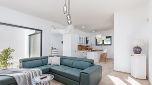 A modern living room with a sectional sofa, a small round coffee table, and a view into the kitchen area. - Gorgeous home in Vintijan with sauna (Vintijan)
