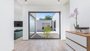 A modern interior with a sliding glass door leading to an outdoor patio, a small plant, and a wicker basket on a wooden console. - Gorgeous home in Vintijan with sauna (Vintijan)
